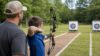 Youth compound bow guide with supervised target practice at an outdoor archery range